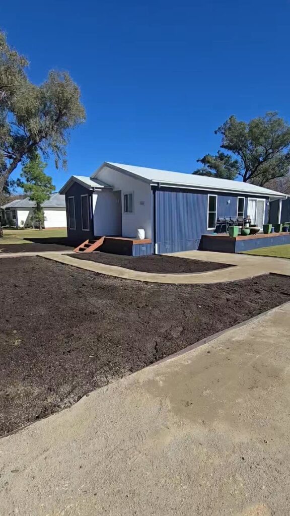 Front yard of a blue home levelled with soil ready for new turf
