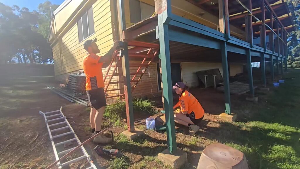 Two workers in hi-vis fitting new stringers to external house stairs